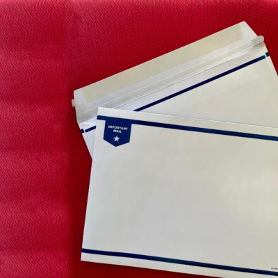A stack of white envelopes with blue borders and a label in the top left corner that reads ‘IMPORTANT MAIL’ with a star symbol. The envelopes are on a textured red background, slightly fanned out to display the multiple items in the stack.